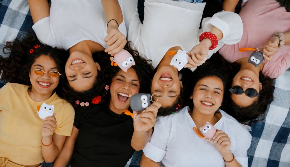 Group of friends smiling with their HerOwlie safety keychains